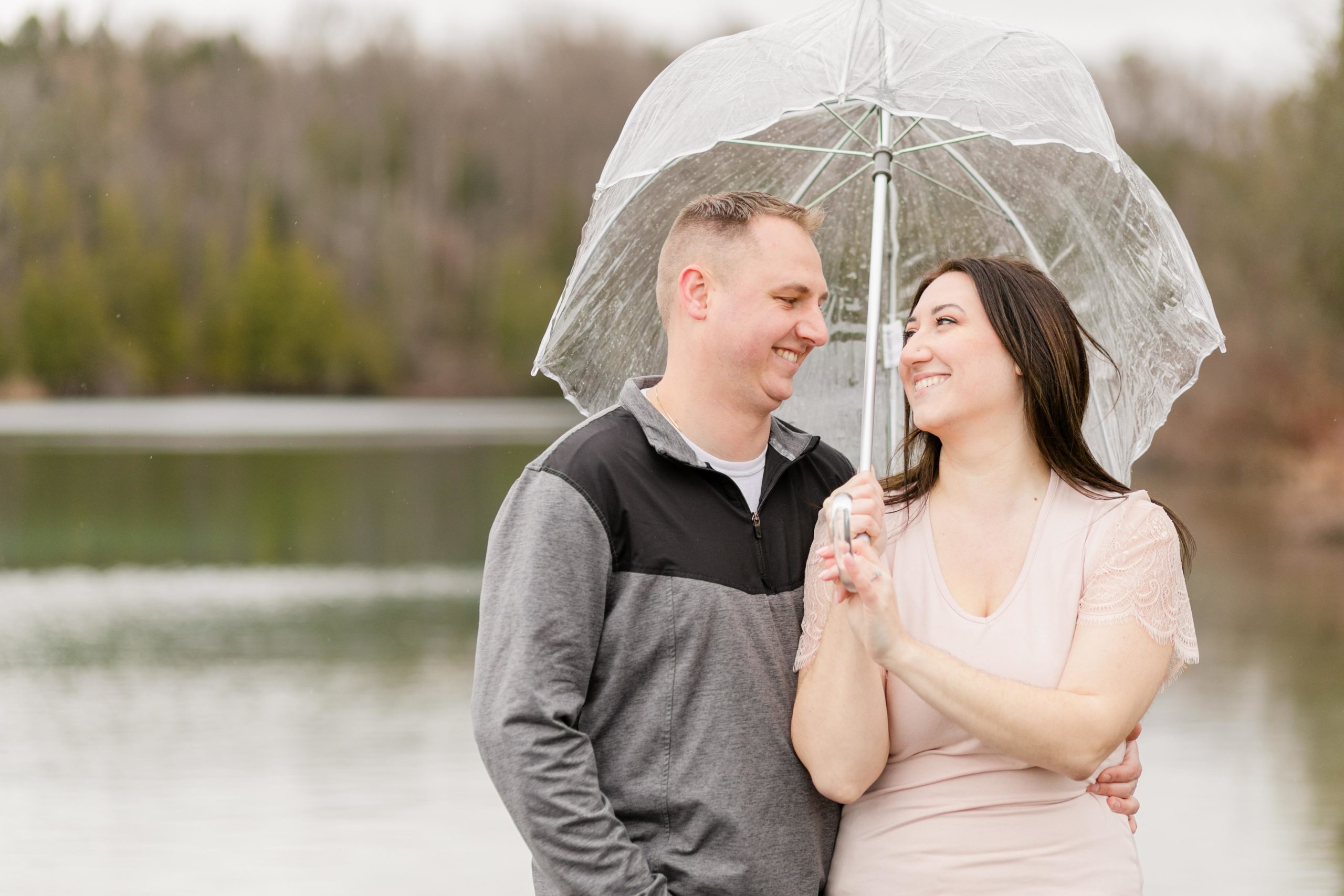 Couple standing next to each other at Green Lakes with an umbrella in the rain at their engagement session