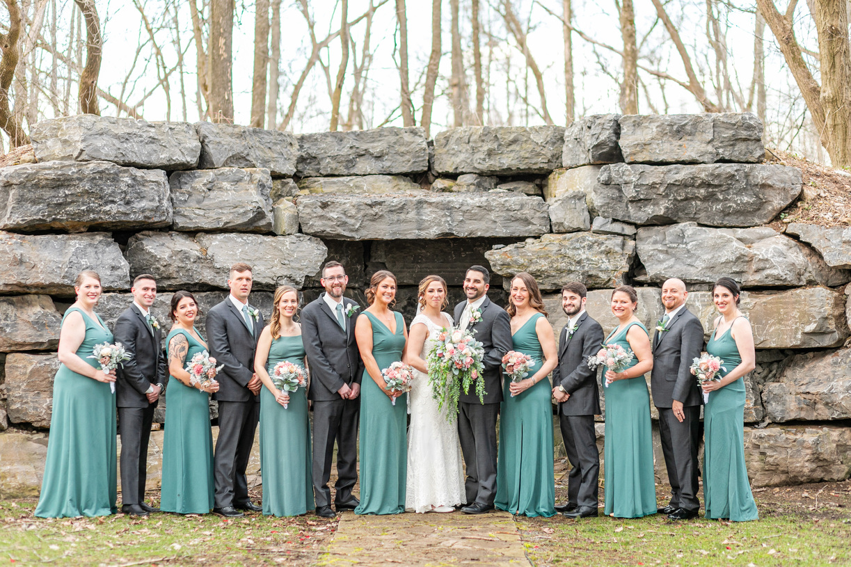 Bridal party in the woods in front of stone structure in Upstate NY