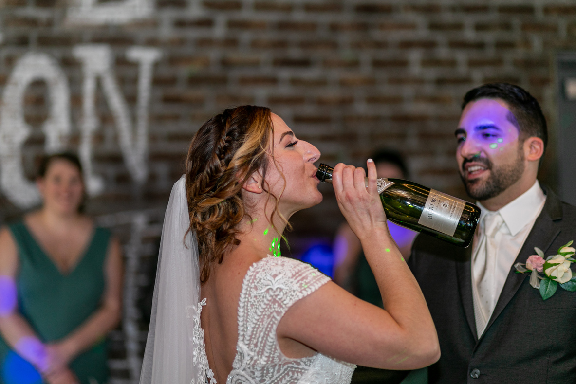 bride drinking champagne from the bottle during the first dance