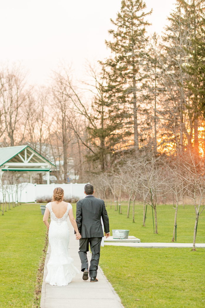 bride and groom walking away from the camera holding hands at golden hour taken by a Upstate NY Wedding Photographer