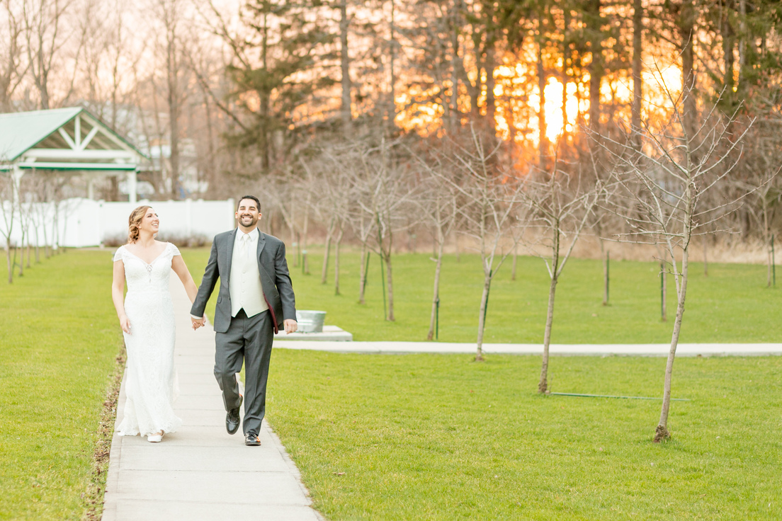 bride and groom walking holding hands during golden hour in Upstate NY
