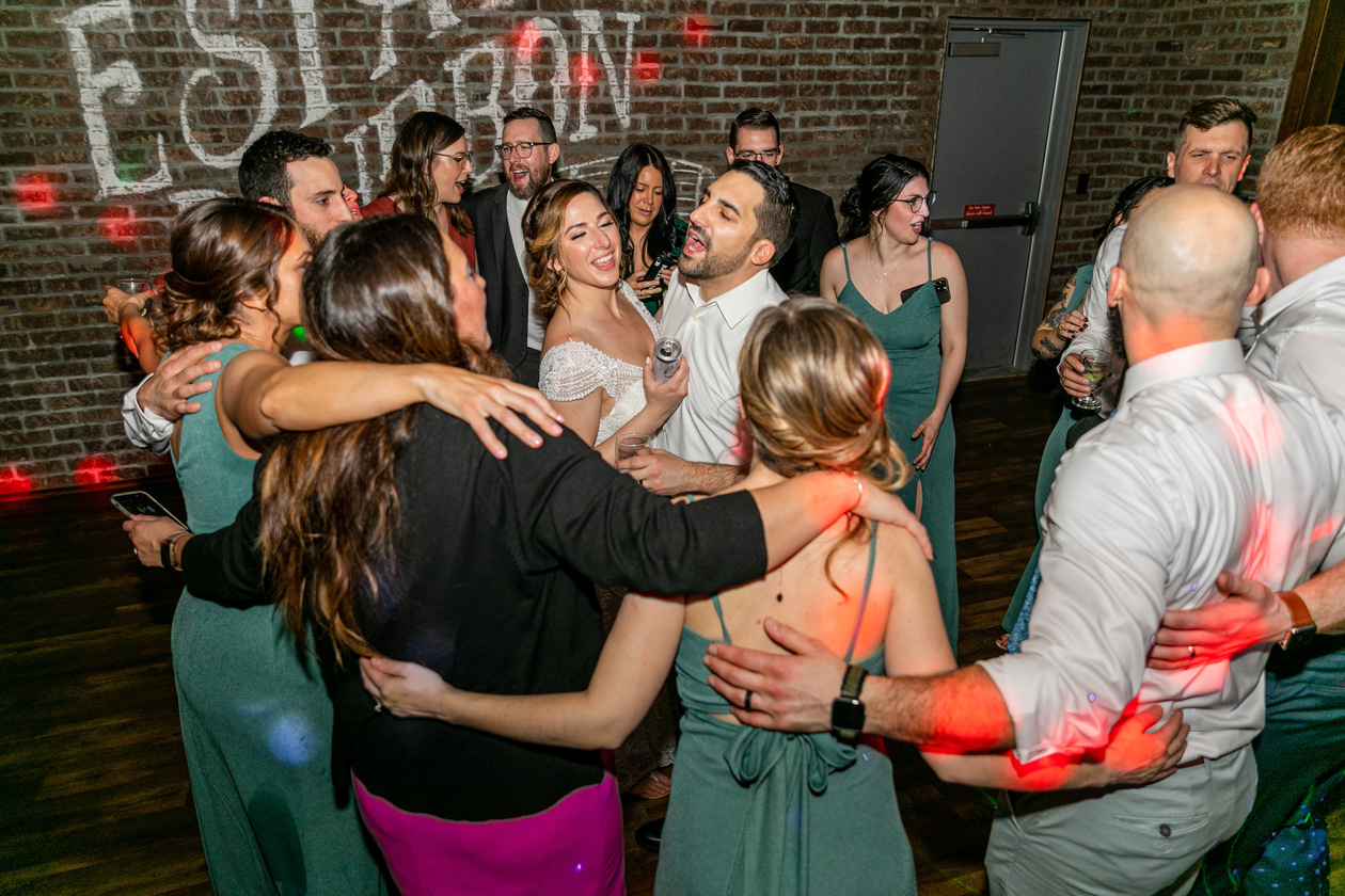 Bride and groom surrounded by friends on the dance floor during reception