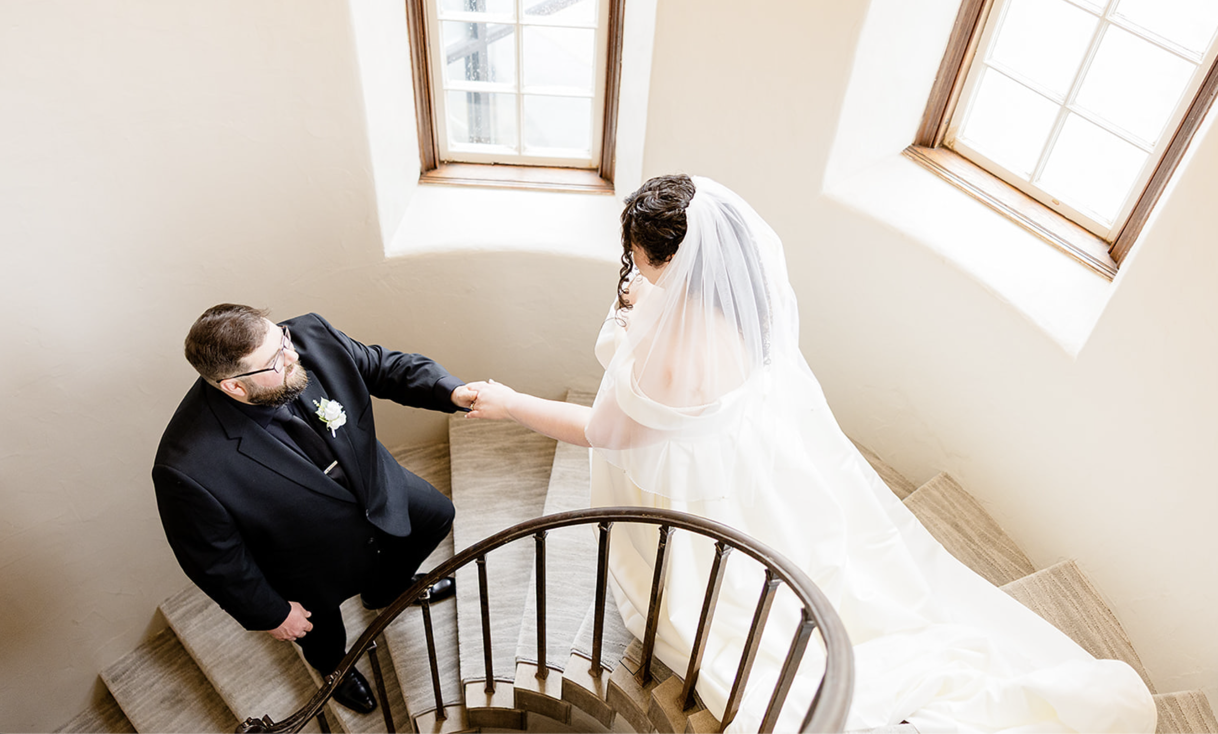 Bride and groom walking down elegant staircase together.